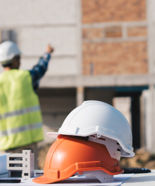 Structural engineer and architect working with blueprints discuss at the outdoors construction site.